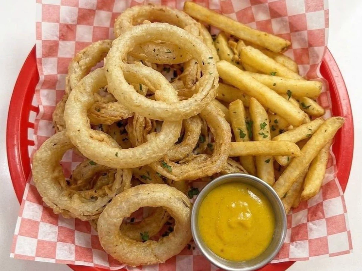 Aros de cebolla rebozados, papas fritas y salsa.